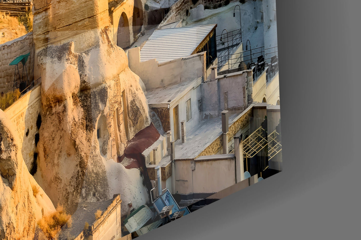 Aerial view of weathered whitewashed buildings nestled into golden stone cliffs in Cappadocia, Turkey.