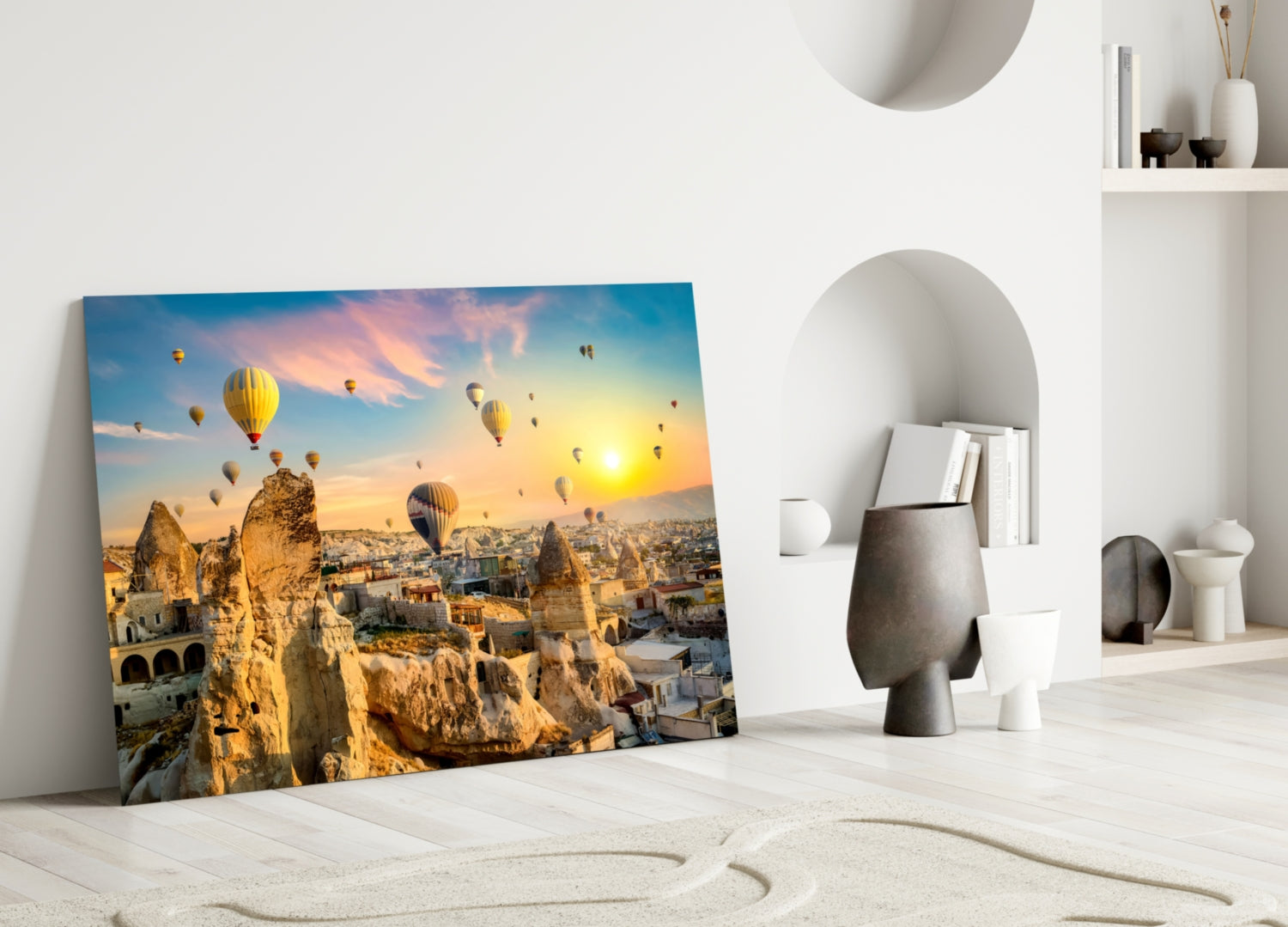 Cappadocia glass wall art leaning against white wall, displaying hot air balloons over rocky landscape at sunset.