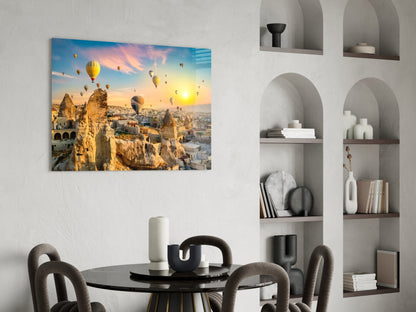 Glass wall art depicting hot air balloons over Cappadocia's rock formations at sunrise, displayed above a dining table in a modern interior.