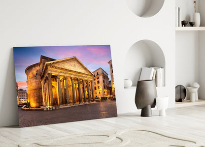 Pantheon glass wall art leaning against white wall in minimalist room with sand sculpture and ceramic vessels.