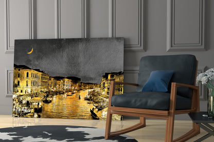 Venetian glass wall art depicting a nighttime golden-lit canal scene with crescent moon, displayed leaning against a white paneled wall beside a wooden chair.