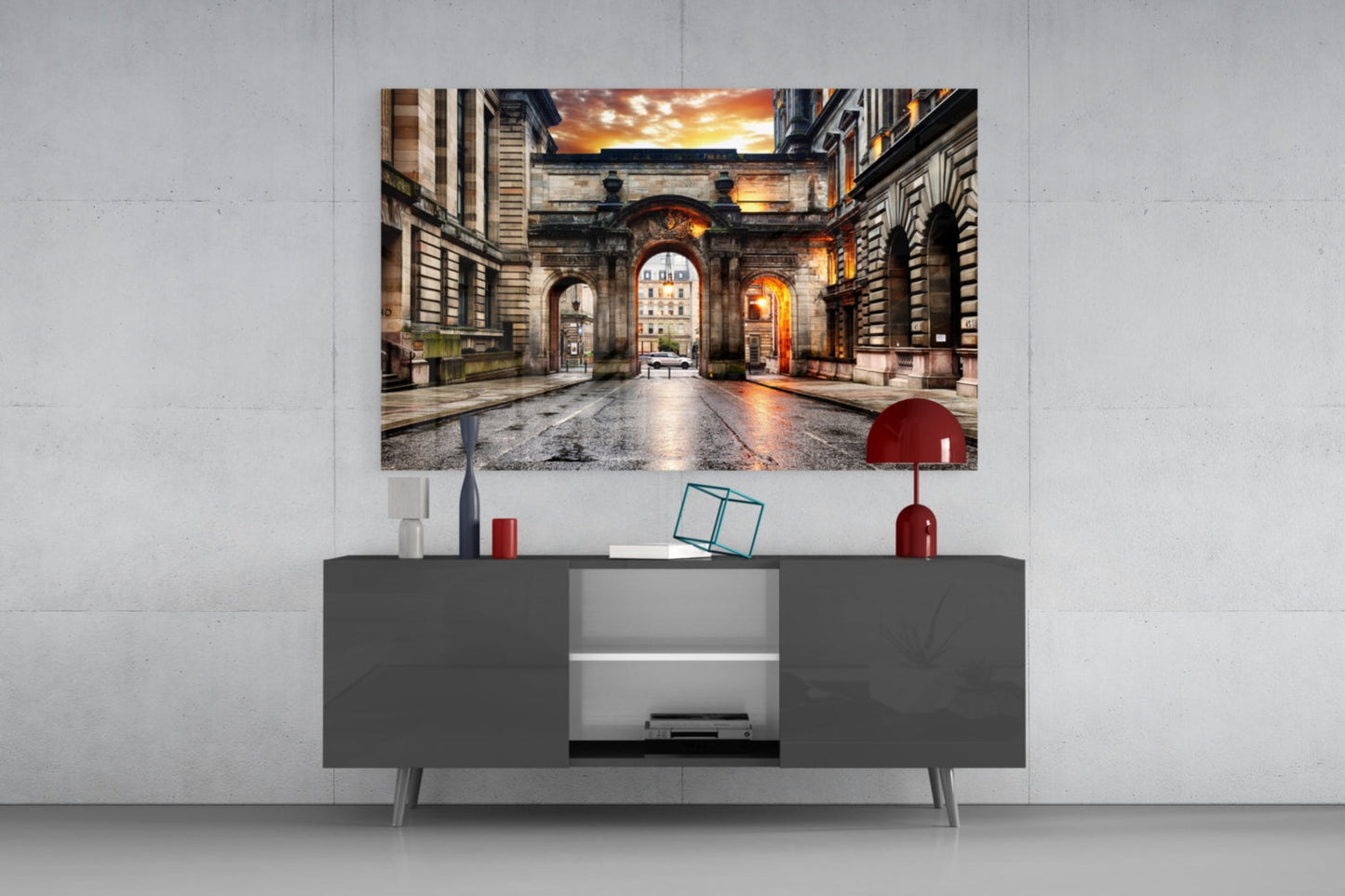 George Square Glass Wall Art displayed above a dark grey TV console, showing an illuminated European courtyard at sunset with architectural arches.