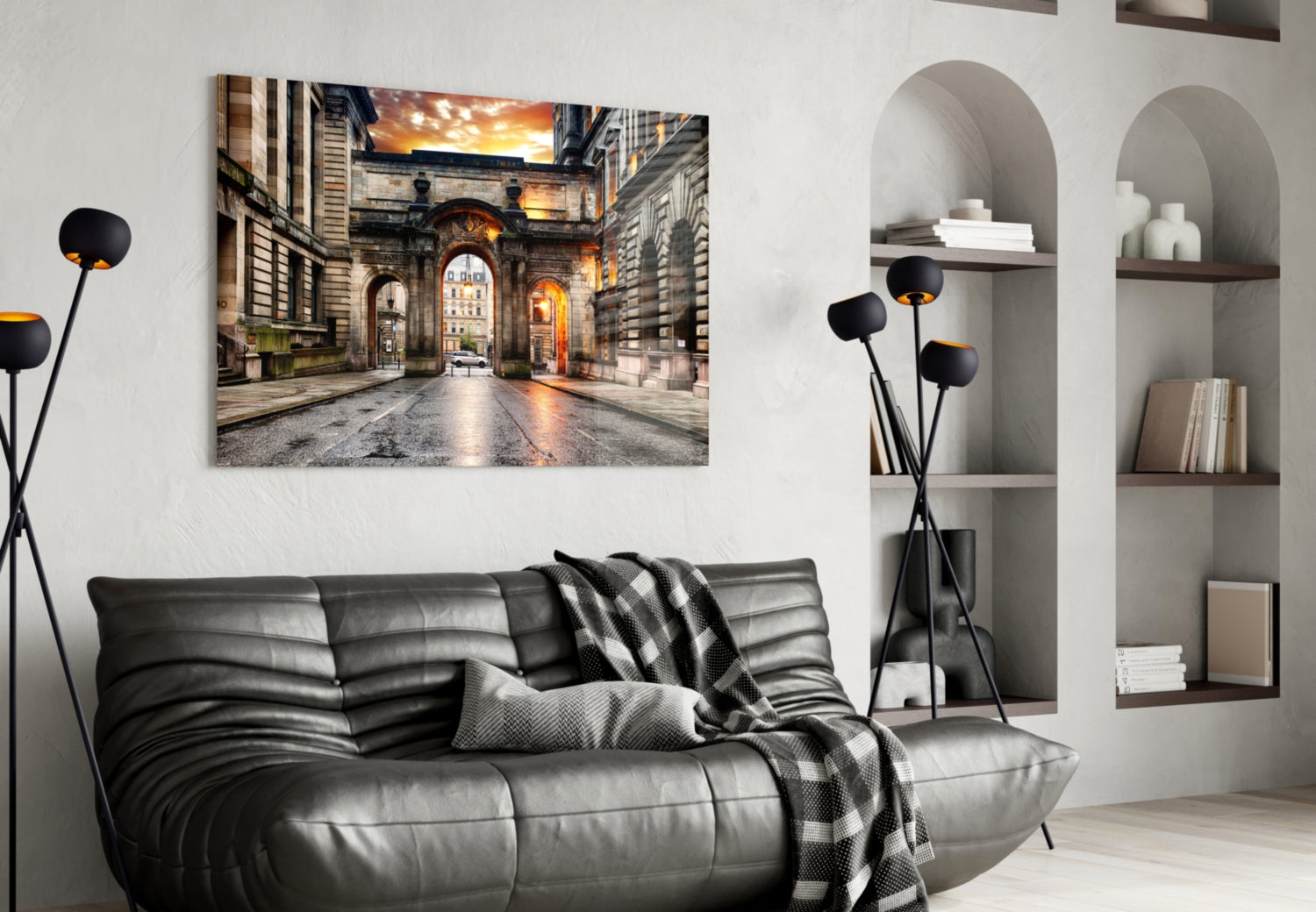 George Square Glass Wall Art displaying a golden-hour photograph of a historic European courtyard with arched passages, mounted above a black leather sofa in a modern living room.