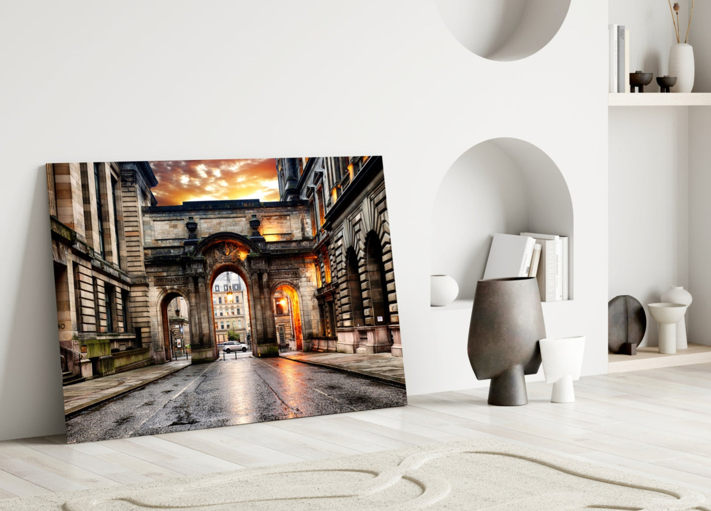 George Square glass wall art leaning against white wall in minimalist room with decorative objects and curved sand pattern floor.