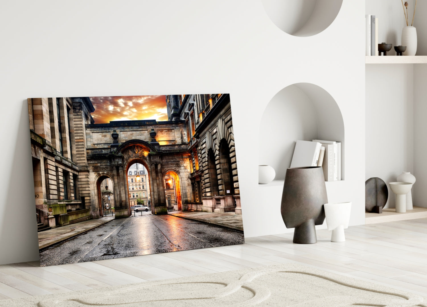 George Square glass wall art leaning against white wall in minimalist room with decorative objects and curved sand pattern floor.