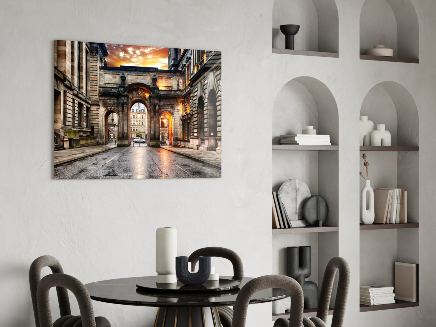 Illuminated European archway at sunset displayed as glass wall art above round black dining table with grey chairs.