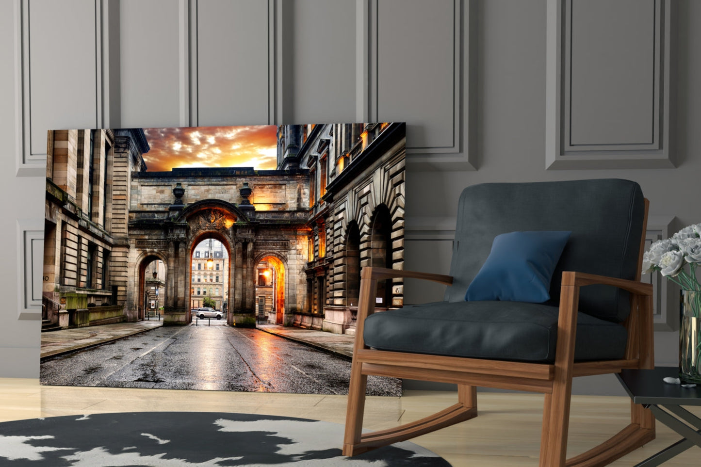 George Square Glass Wall Art displayed on living room wall showing illuminated stone archway at dusk with golden sky, positioned above wooden rocking chair.