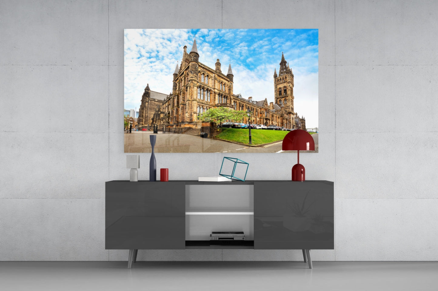 University of Glasgow glass wall art displaying the golden sandstone building and tower against blue sky, mounted above a dark console table with decorative accessories.