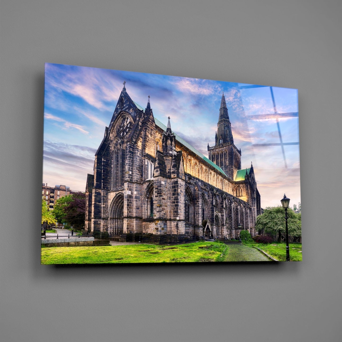 Glasgow Cathedral's Gothic stone facade with illuminated spires displayed on a glass wall art panel against gray wall.