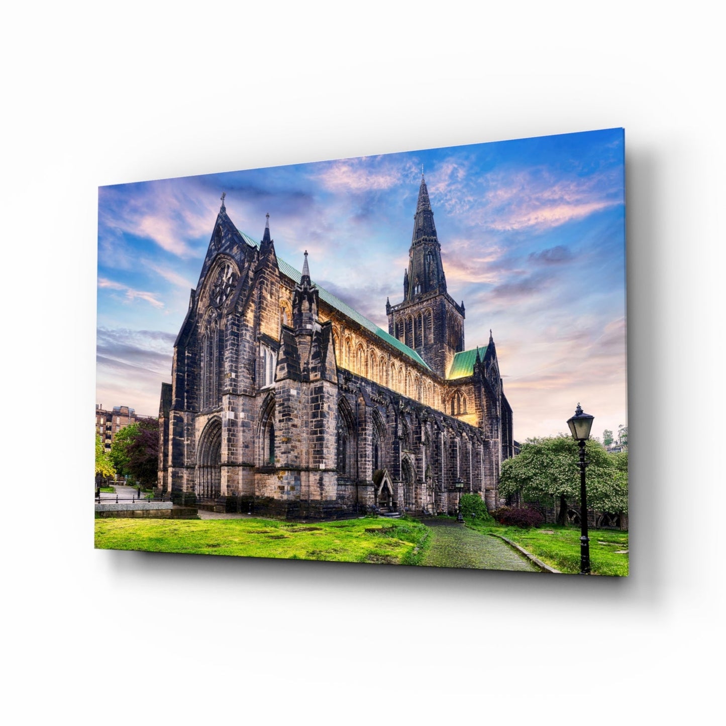 Glass wall art print of Glasgow Cathedral at dusk, featuring illuminated Gothic architecture with green grounds and twilight sky.