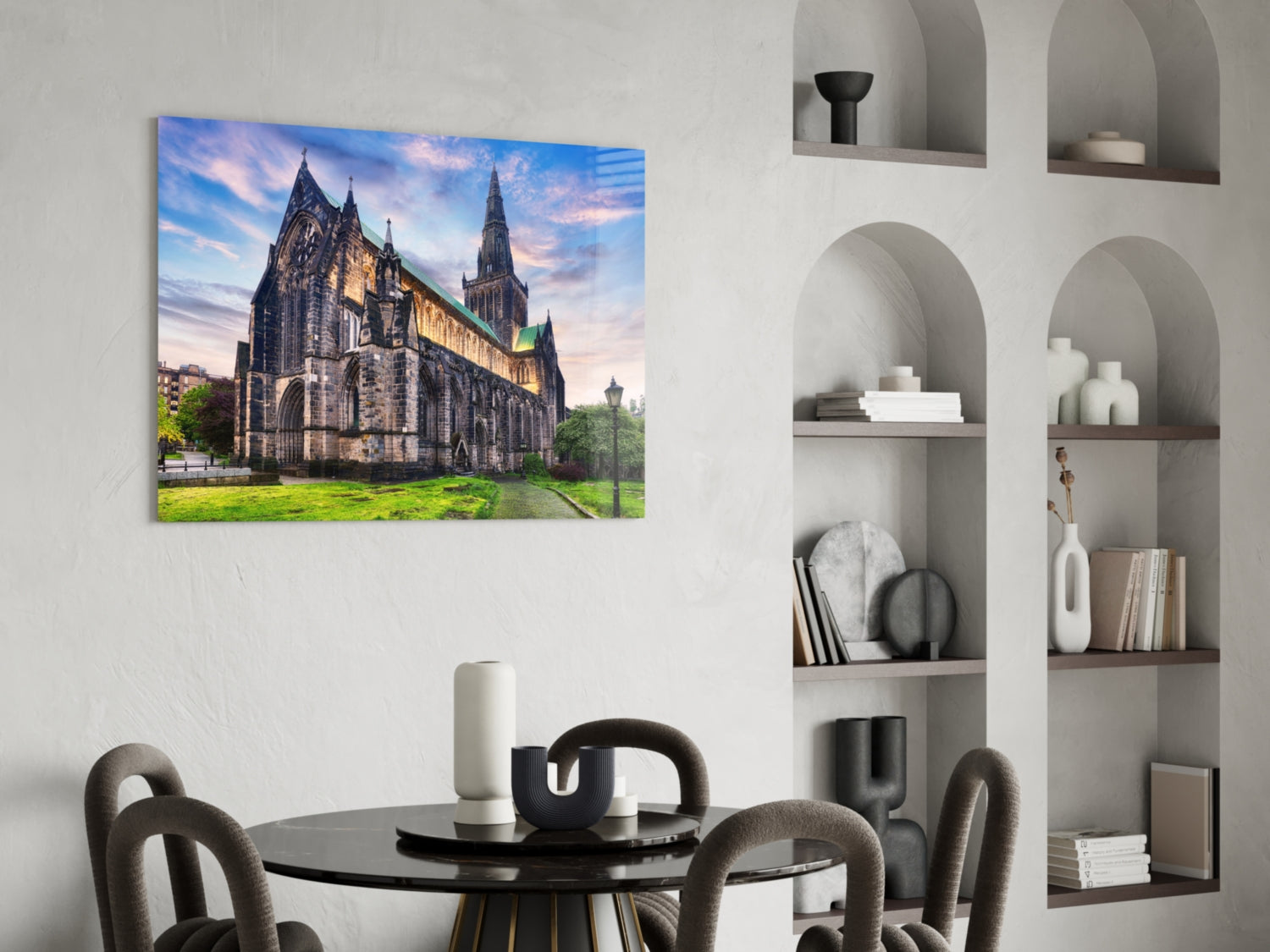 Glass wall art print of Glasgow Cathedral at dusk displayed above a black dining table in a minimalist interior setting.