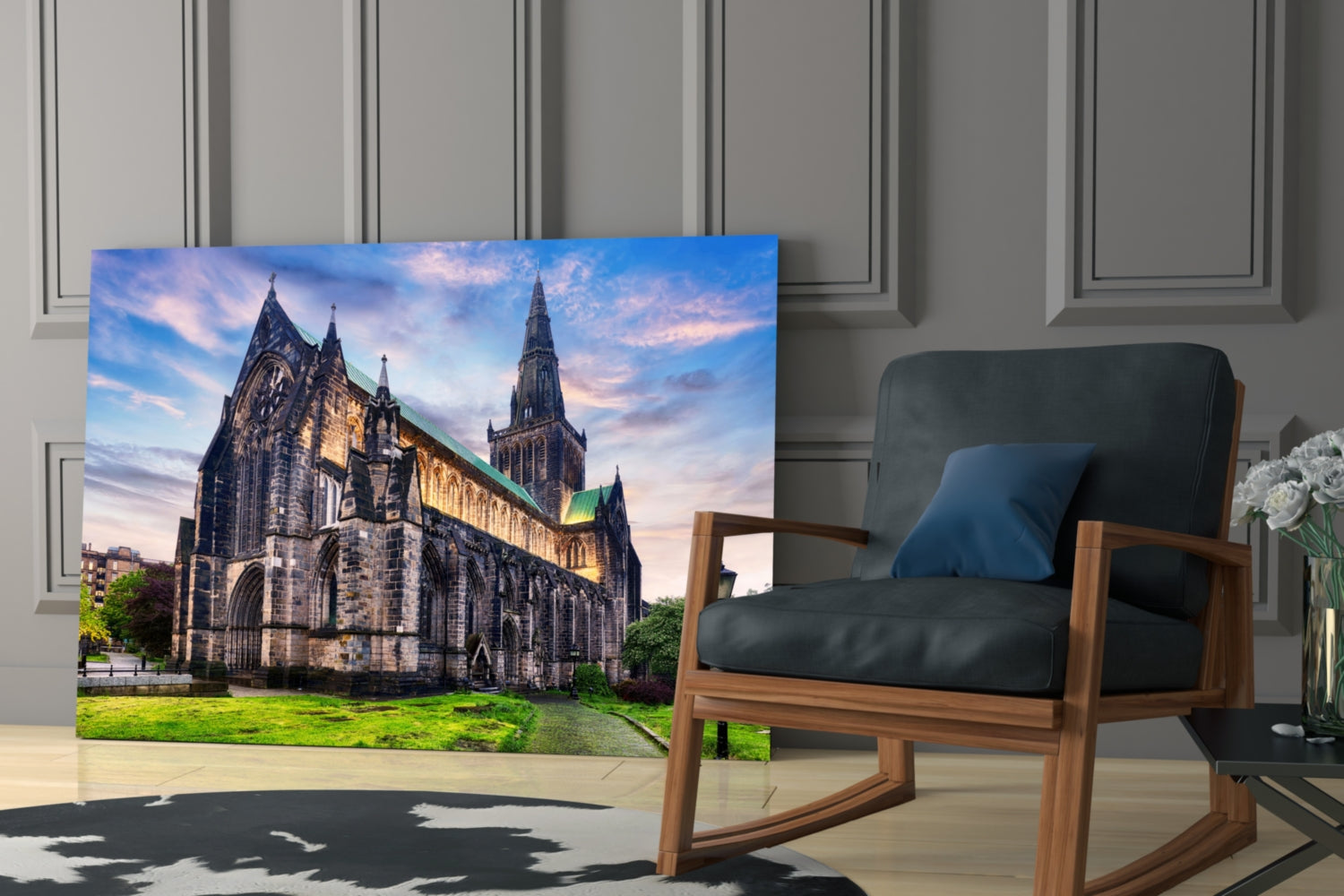 Glass wall art featuring Glasgow Cathedral with green grounds and blue sky, displayed in modern living room beside wooden chair.