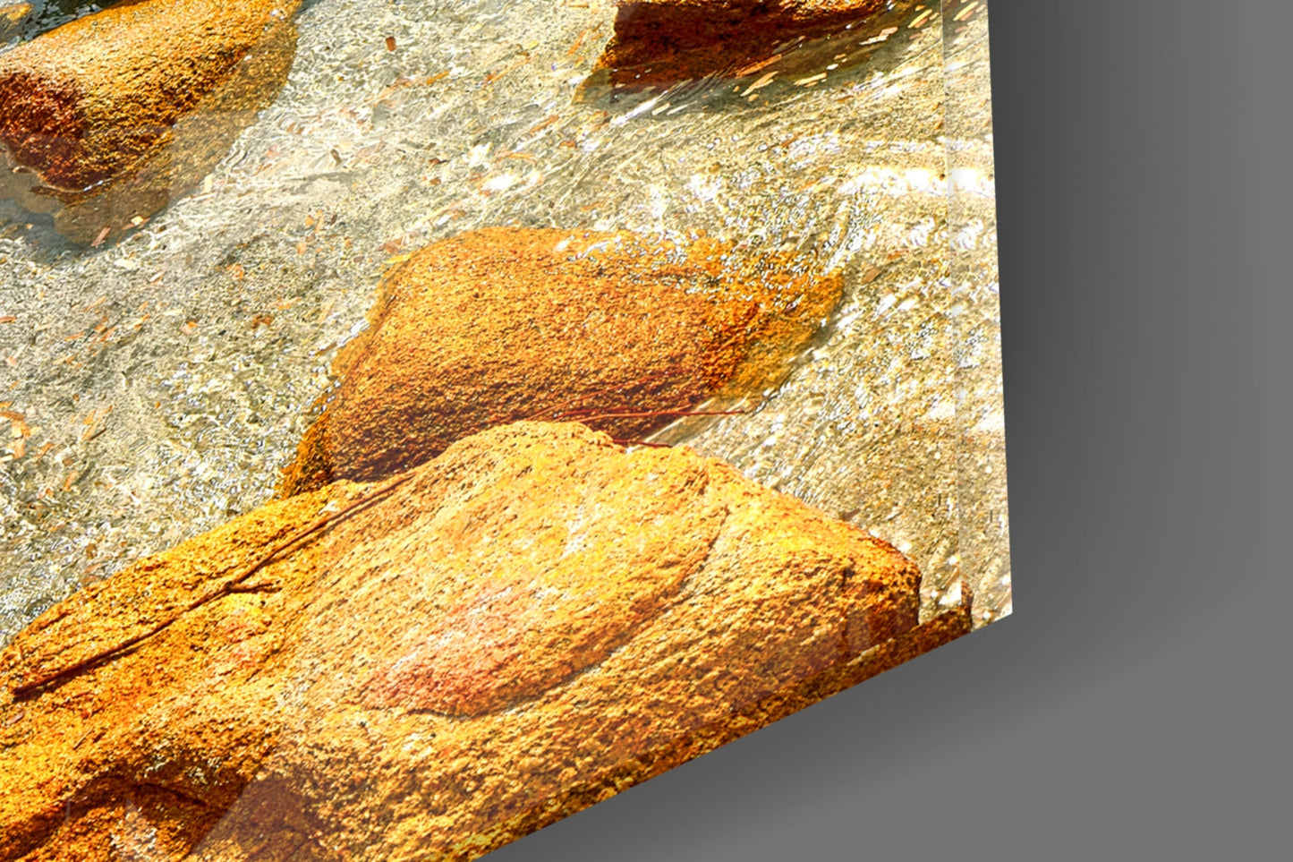 Close-up detail of textured glass surface showing golden-yellow and rust-orange mineral deposits with white crystalline formations against gray background.