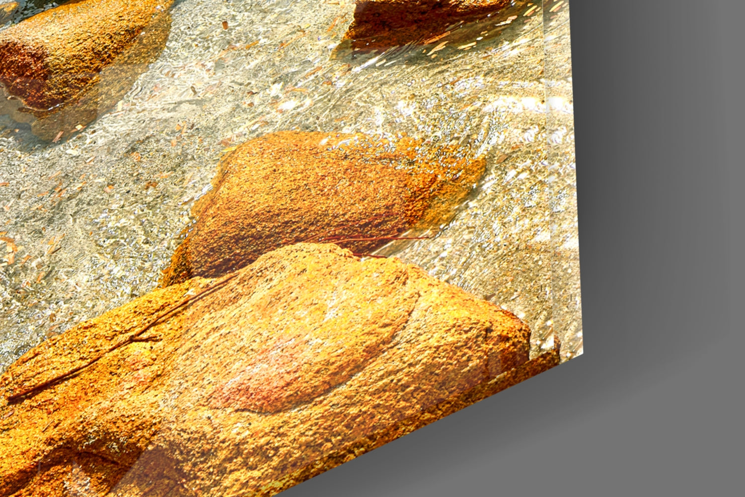 Close-up detail of textured glass surface showing golden-yellow and rust-orange mineral deposits with white crystalline formations against gray background.