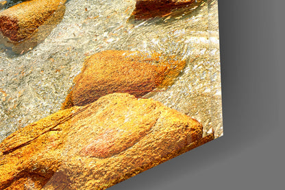 Close-up detail of textured glass surface showing golden-yellow and rust-orange mineral deposits with white crystalline formations against gray background.