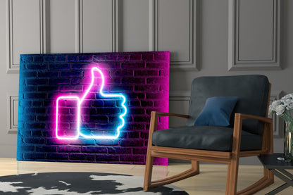 Neon thumbs-up sign in pink and blue glowing against brick wall, displayed in modern living room with wooden chair.