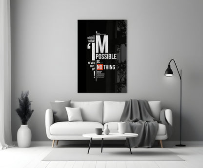Black motivational glass wall art with white and red text reading "I'm Possible is Nothing" displayed above a white sofa in a minimalist living room.