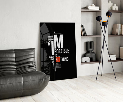 Black motivational glass wall art displaying white and orange text reading "I'm Possible Is... Never Give Up" in a modern living room setting.
