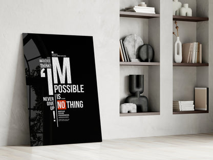 Black motivational glass wall art leaning against white wall beside shelving unit displaying decorative items and books.