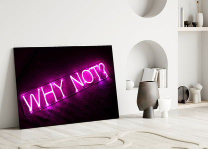 Magenta neon "WHY NOT?" glass wall art leaning against white wall in minimalist interior setting.
