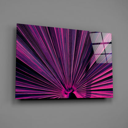 Modern glass wall art with radiating pink and magenta lines converging toward center on black background, displayed at angle against gray wall.