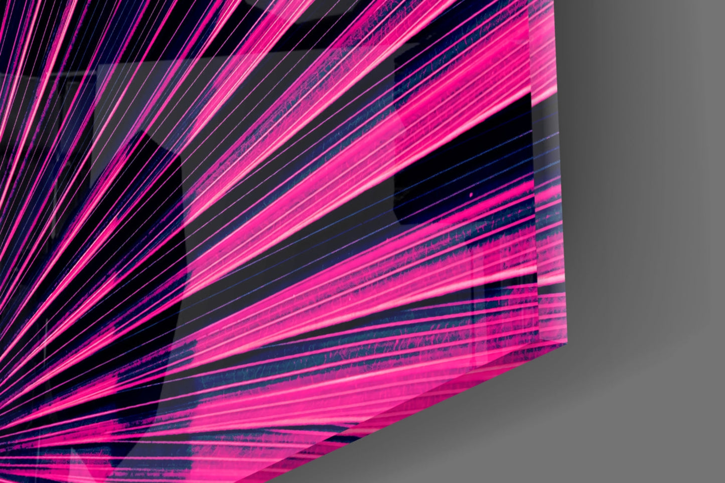 Close-up of neon pink and blue glass art with radiating linear streaks and black geometric shapes against gray background.