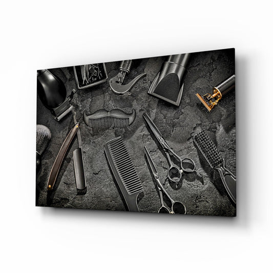 Overhead flat lay of barbering tools arranged on textured gray surface, including scissors, combs, clippers, and brush in black and metallic tones.