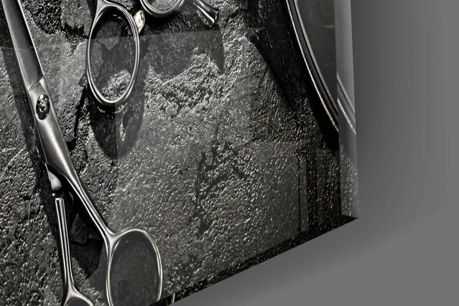Close-up of barber scissors on textured gray surface, black and white photograph showing metal handles and blades in detail.