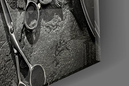 Close-up of barber scissors on textured gray surface, black and white photograph showing metal handles and blades in detail.