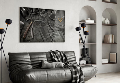 Black and white barber tools glass wall art hanging above a gray leather sofa in a modern living room interior.
