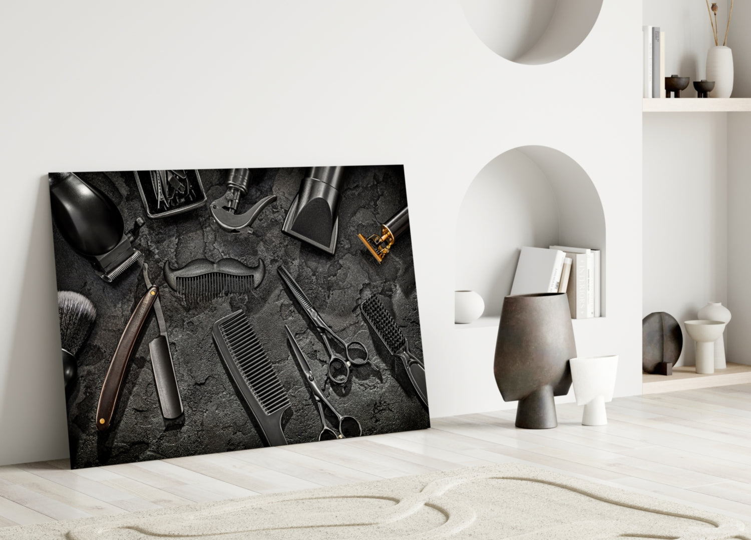 Black and white glass wall art displaying barbering tools arranged on dark textured background, leaning against white interior wall.