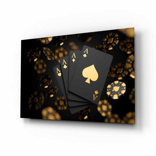 Four black playing cards with gold aces and suit symbols arranged on dark background with blurred gold casino chips.