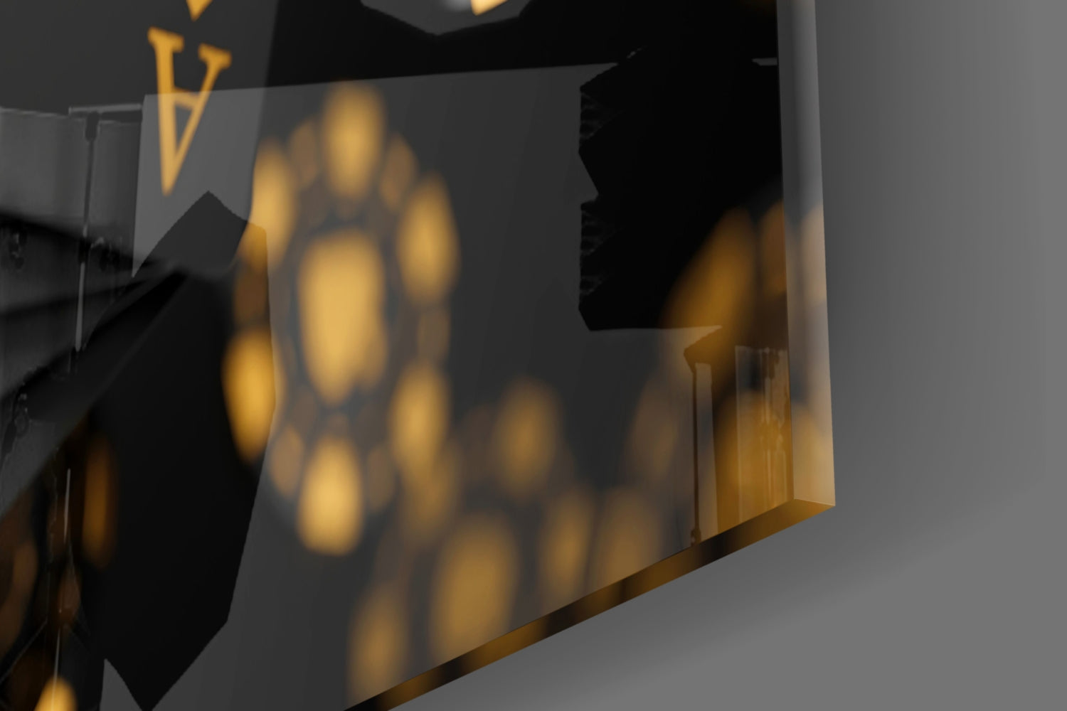 Close-up angled view of gold and black glass wall art with circular bokeh pattern and brass accents, showing depth and translucence.