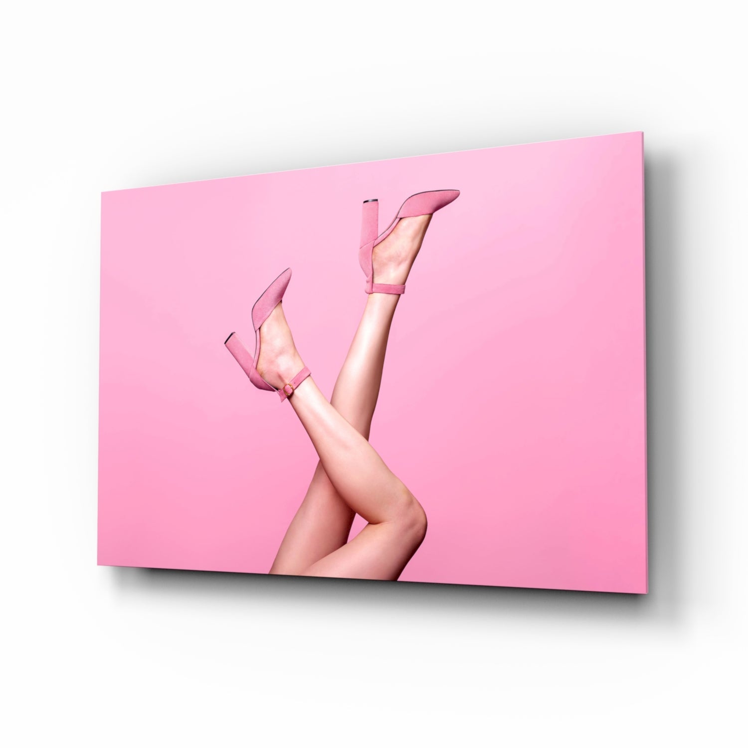 Pair of legs wearing pink high heels crossed against solid pink background on glass wall art panel.
