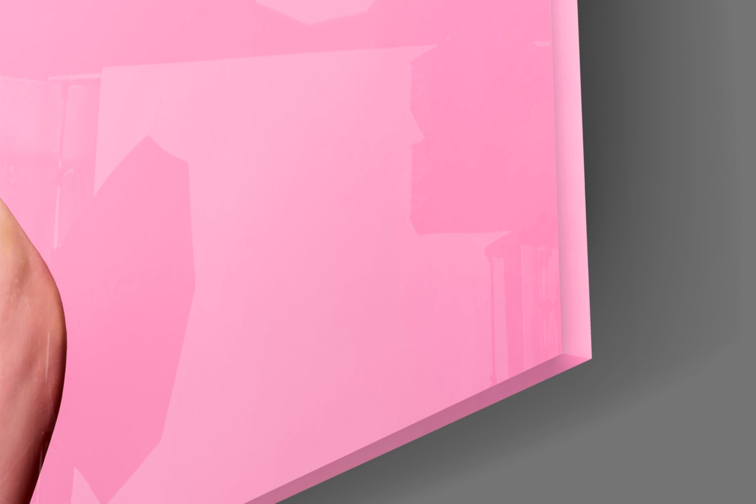Close-up detail of pink glass wall art showing smooth surface texture and curved edge against gray background.
