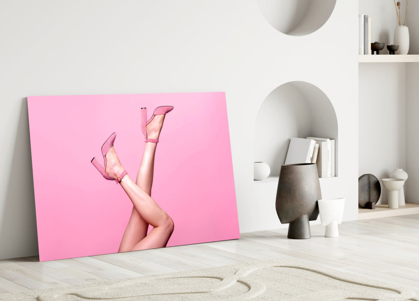 Pink glass wall art leaning against white wall displays woman's legs in pink heels against bright pink background.