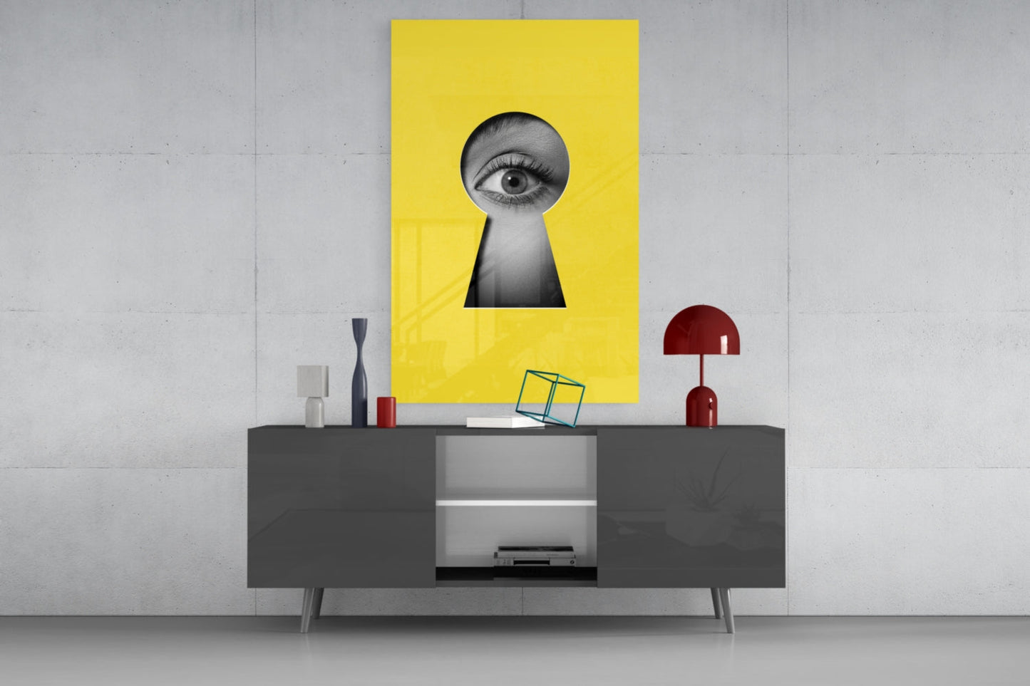 Yellow glass wall art with black and white eye peering through keyhole shape, displayed above gray media console.