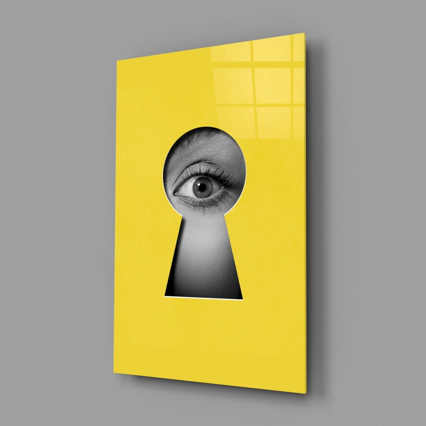 Angled view of yellow security glass wall art featuring a black and white eye peering through a keyhole cutout.
