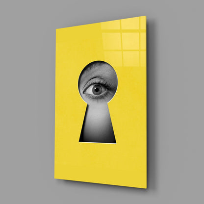 Angled view of yellow security glass wall art featuring a black and white eye peering through a keyhole cutout.