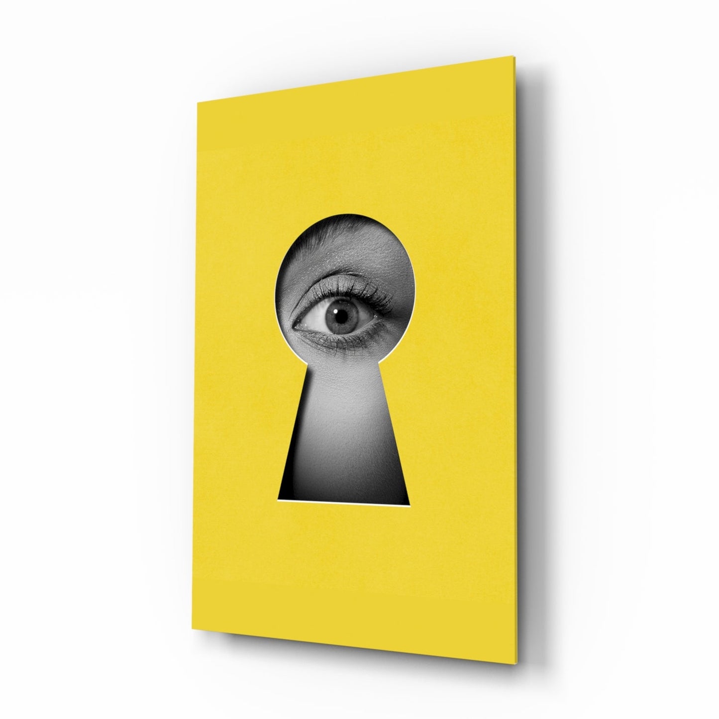 Yellow glass wall art panel with keyhole-shaped cutout revealing black and white close-up of human eye.