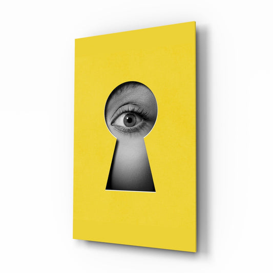 Yellow glass wall art panel with keyhole-shaped cutout revealing black and white close-up of human eye.