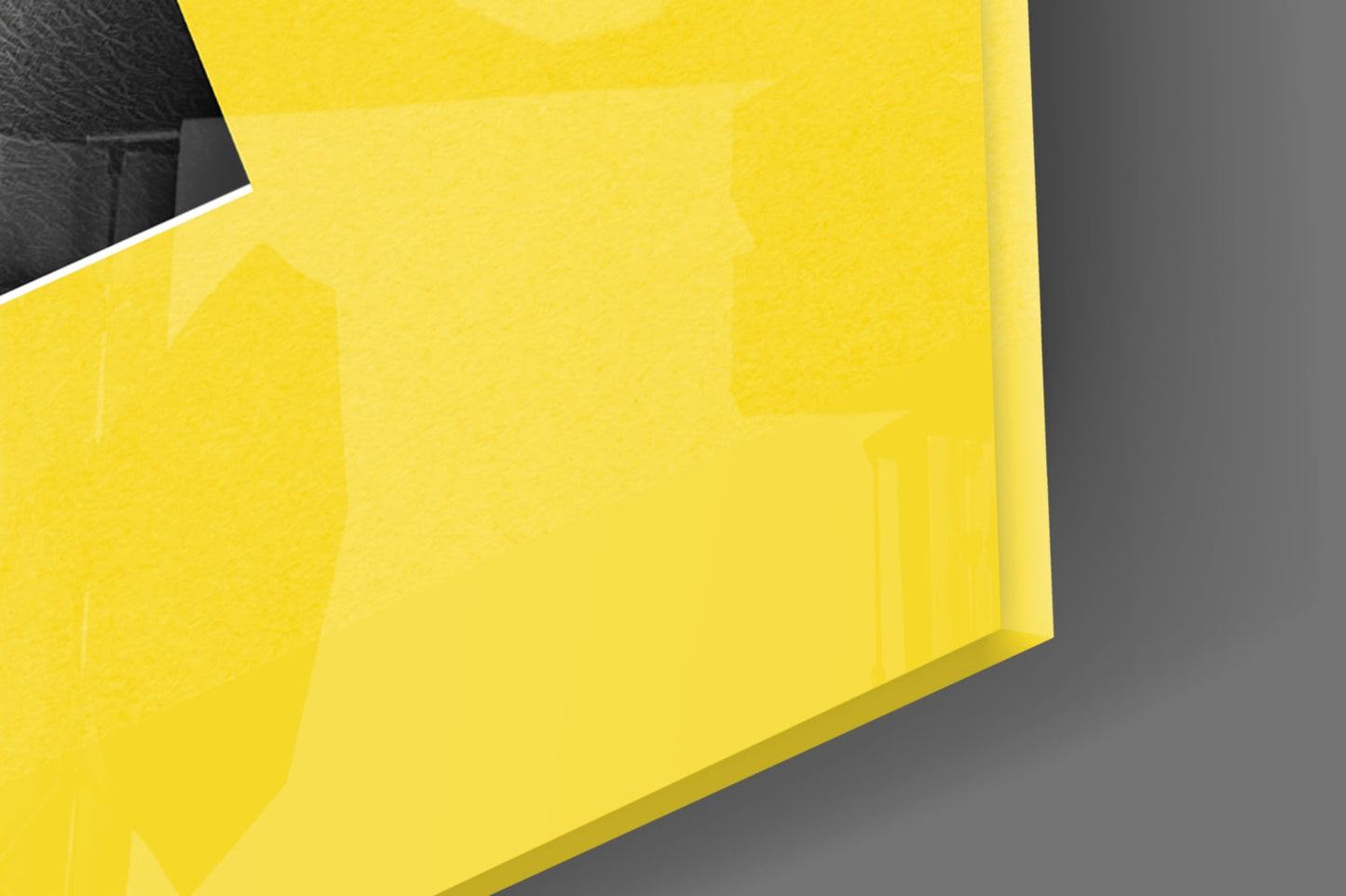 Close-up angled view of bright yellow security glass panel against gray background, showing glossy surface and beveled edge.