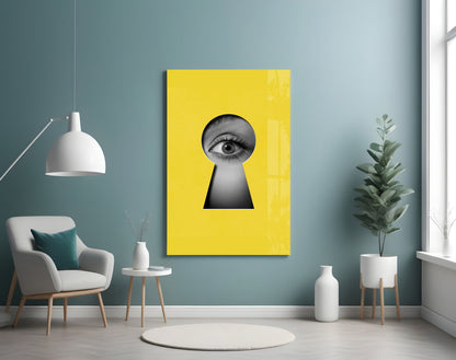 Yellow glass wall art with black and white eye illustration in keyhole shape, displayed in modern room with teal walls.