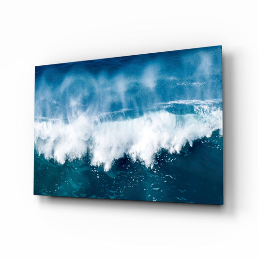 Angled view of glass wall art displaying turbulent ocean waves with white foam against deep teal water.