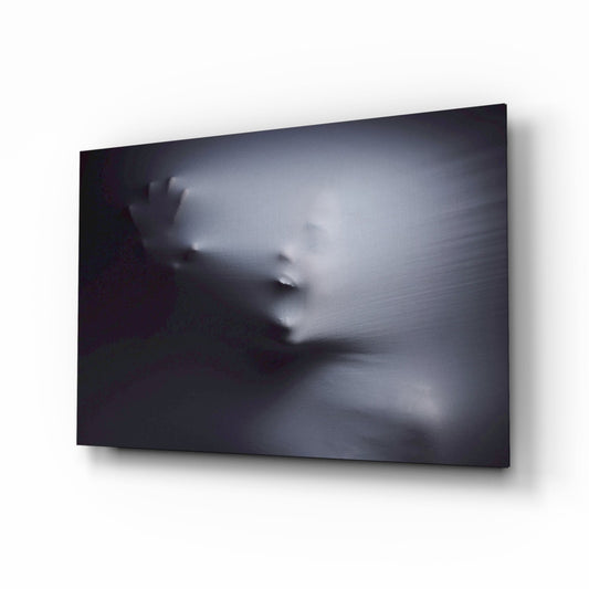 Mounted glass wall art displaying a blurred, ethereal face pressing against translucent fabric in grayscale tones, photographed at an angled perspective.