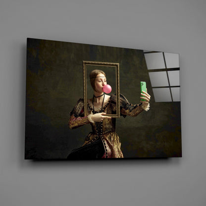 Glass wall art depicting Renaissance-style figure in gold dress holding frame and green phone, blowing pink bubble, mounted on gray wall.