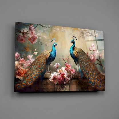Two iridescent blue-headed peacocks with golden-brown tail feathers displayed on glass against pink flowers and warm beige background.