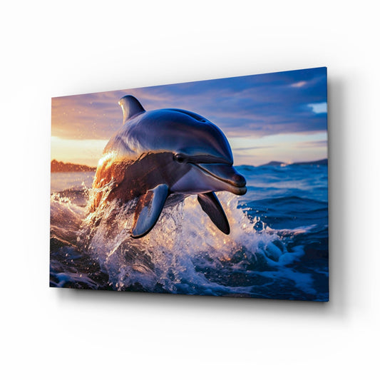 A dolphin leaps through ocean waves at sunset, displayed on a glass wall art panel with warm golden and cool blue tones.