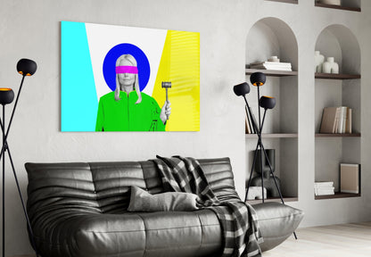 Colorful glass wall art displaying a woman in green jacket with pink blindfold and gavel against cyan and yellow background, hung above black sofa in modern living room.