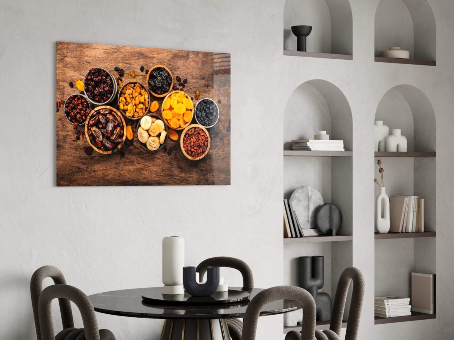 Canvas wall art displaying dried fruits and nuts in bowls on wooden surface, hung above black dining table in modern interior.
